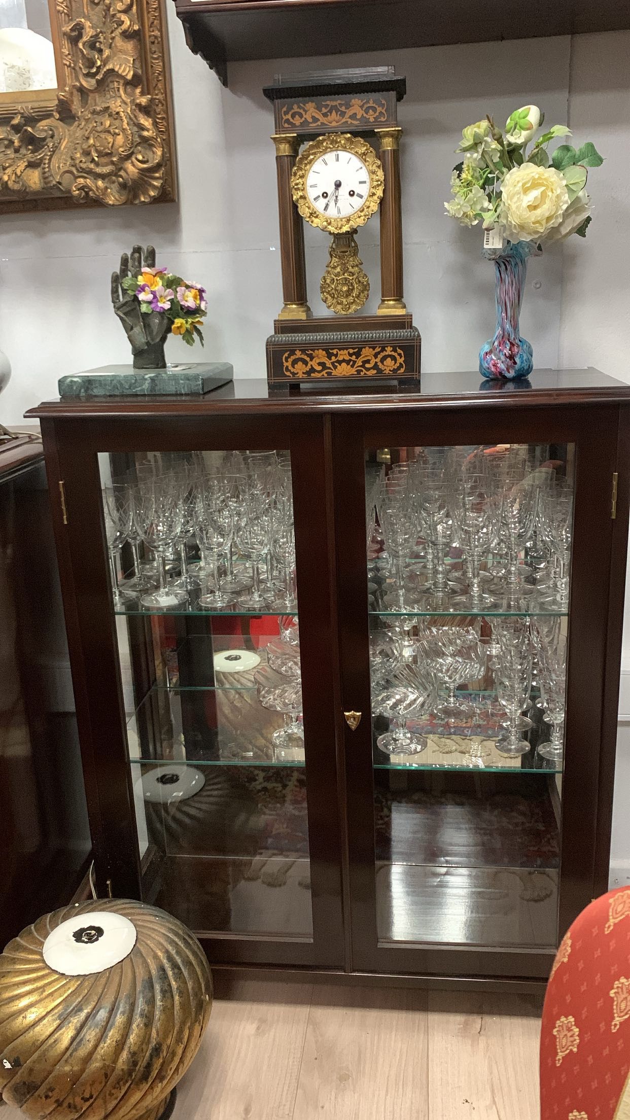 Meuble avec vitrine assez sombre et grande, dans lequel se trouvent de nombreux verres