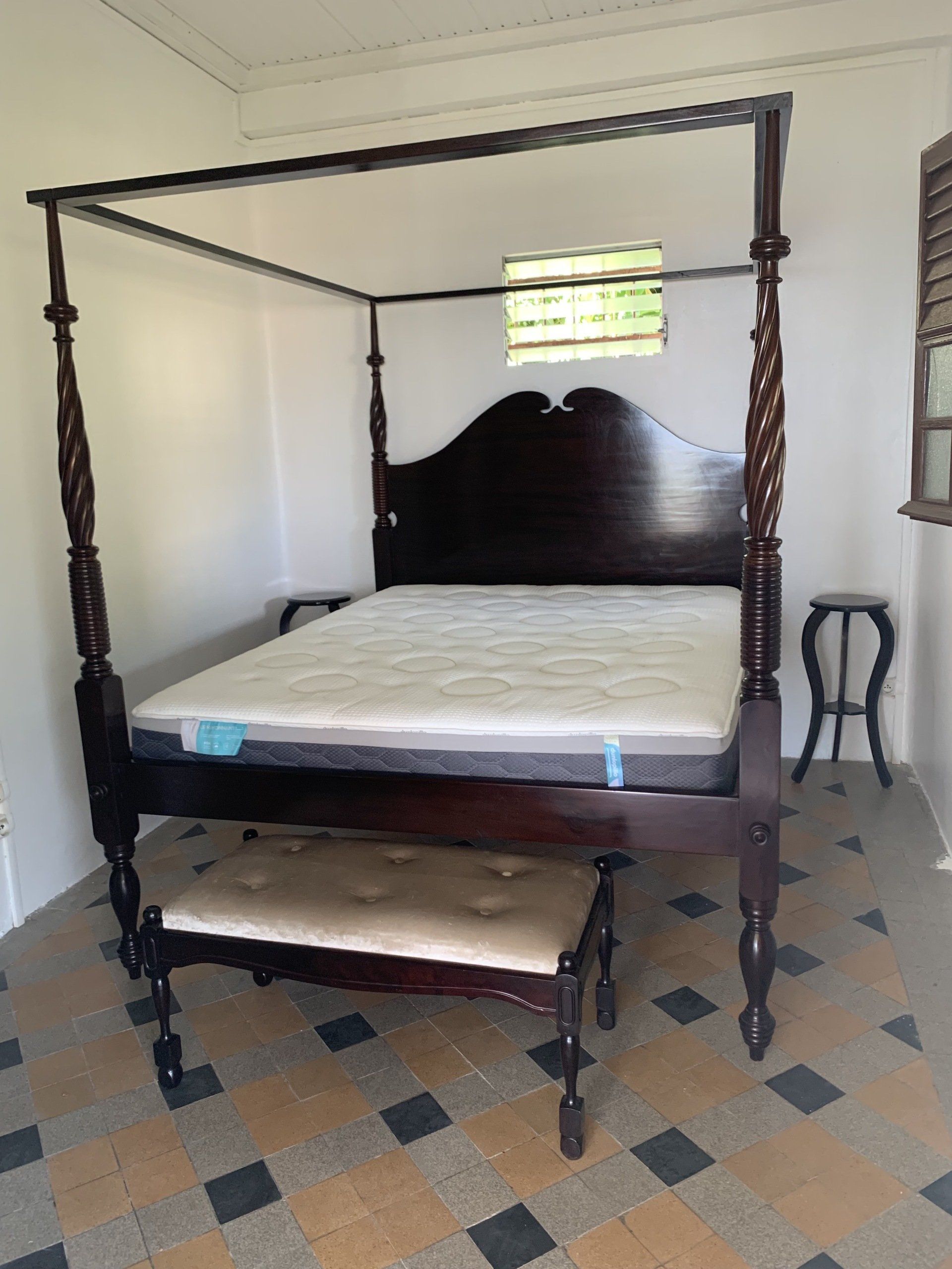 Lit à colonnes à côté d'une toute petite table de nuit