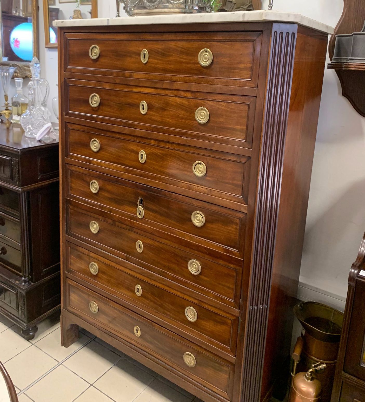 Commode haute en bois sombre avec plateau en marbre et poignées en laiton.