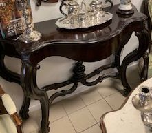 Console ancienne en bois foncé, plateau incurvé, pieds ornés, avec un service à thé en argent posé dessus.