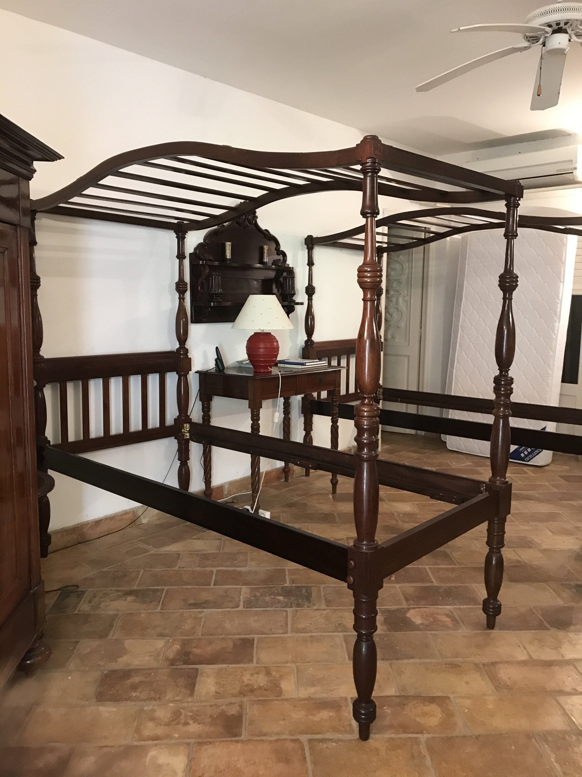 Double structure de lit à baldaquin sur carrelage avec une grande table de nuit entre les deux