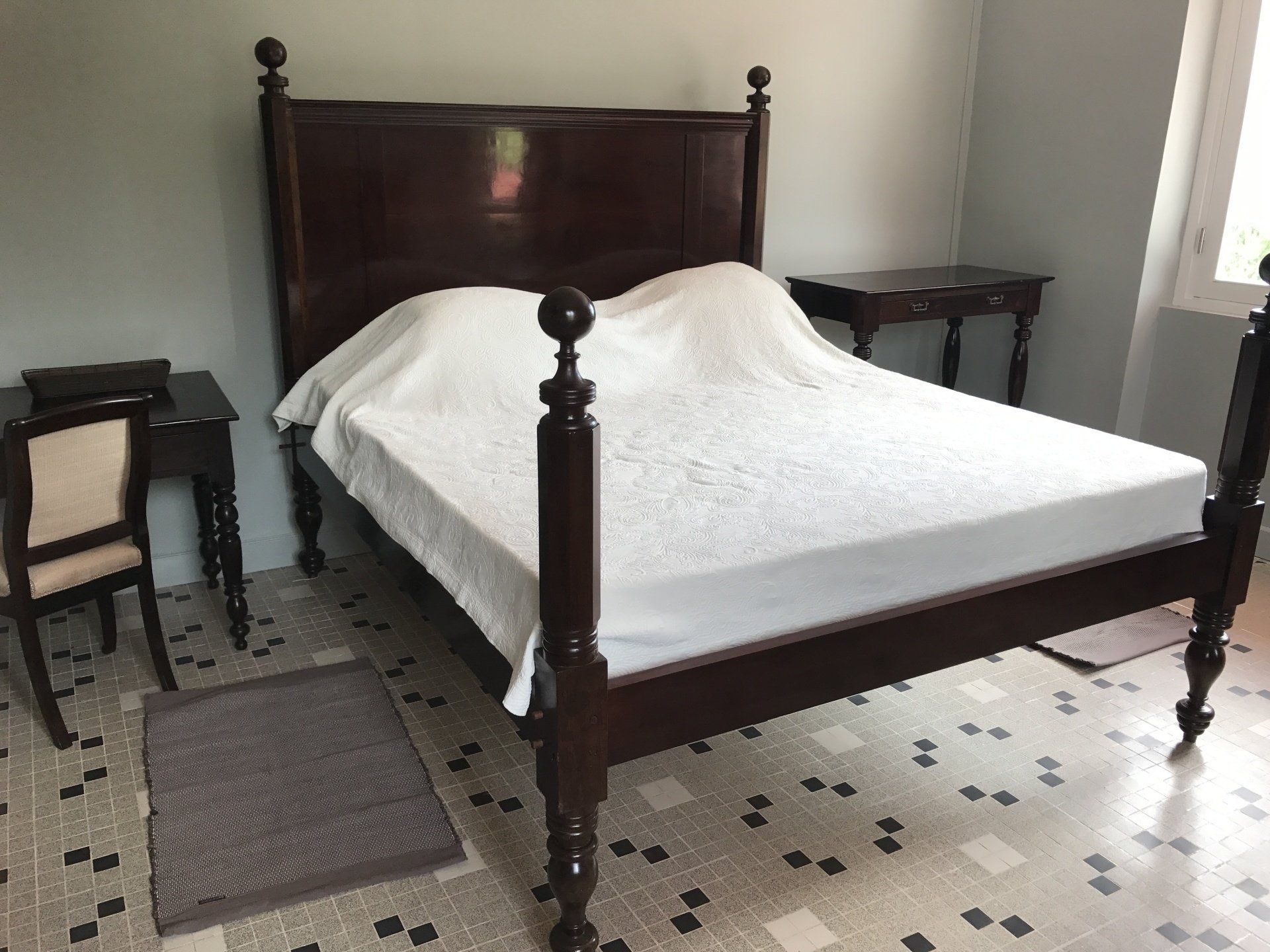 Lit à colonnes avec draps blancs sur carrelage