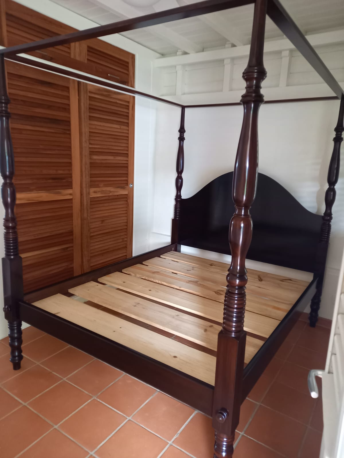 Lit à colonne sans matelas à côté d'une porte d'armoire