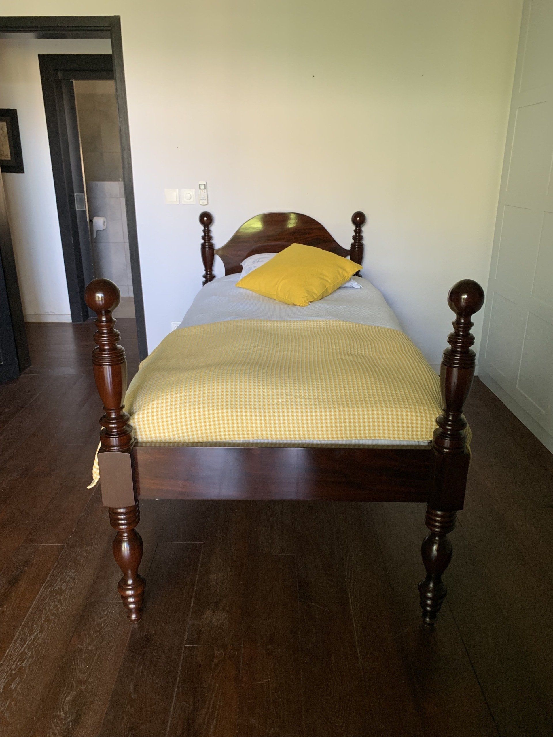 Lit à colonne avec des draps jaunes sur parquet