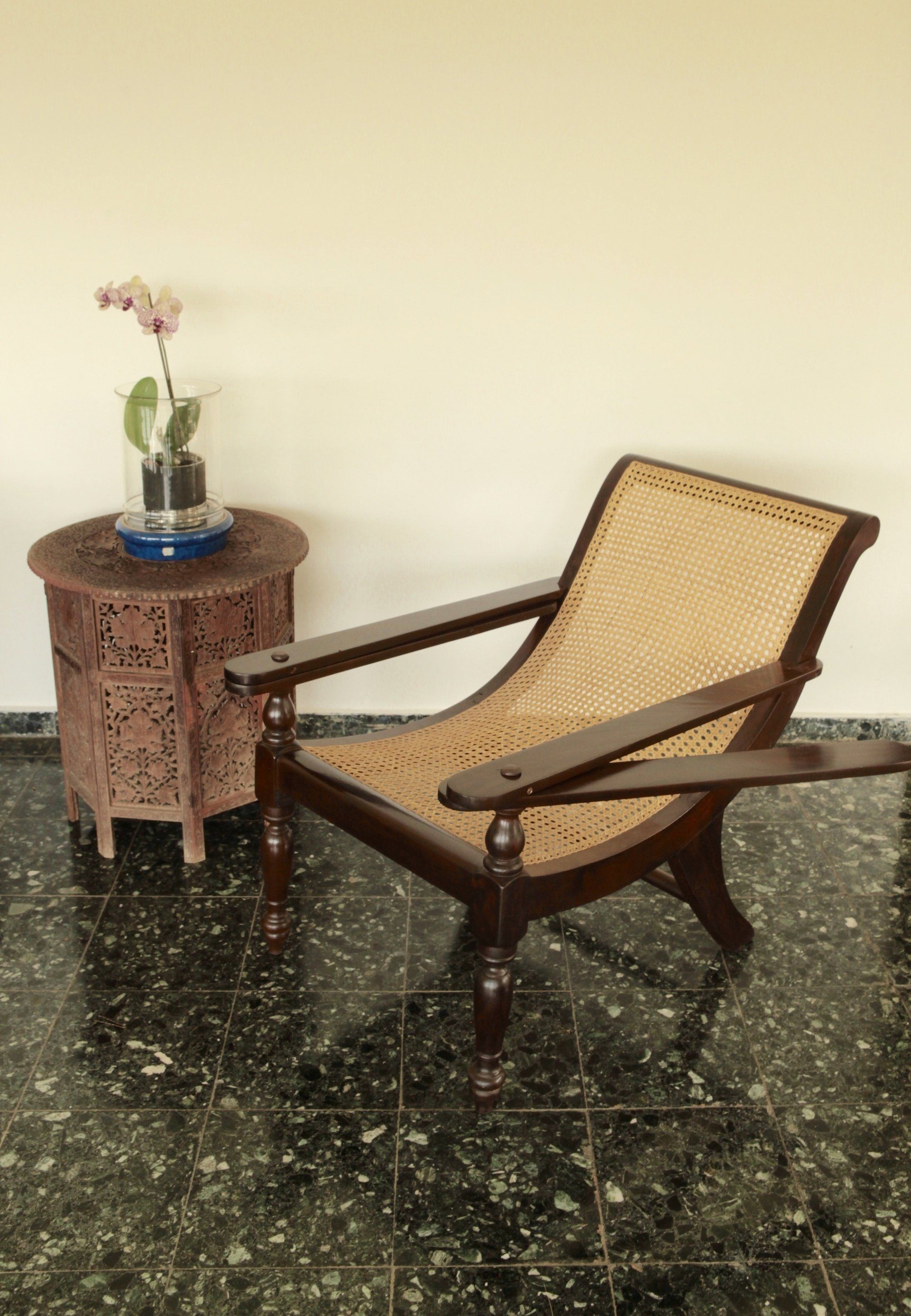 Siège de couleur sombre et crème à côté d'une petite table avec une plante posée dessus