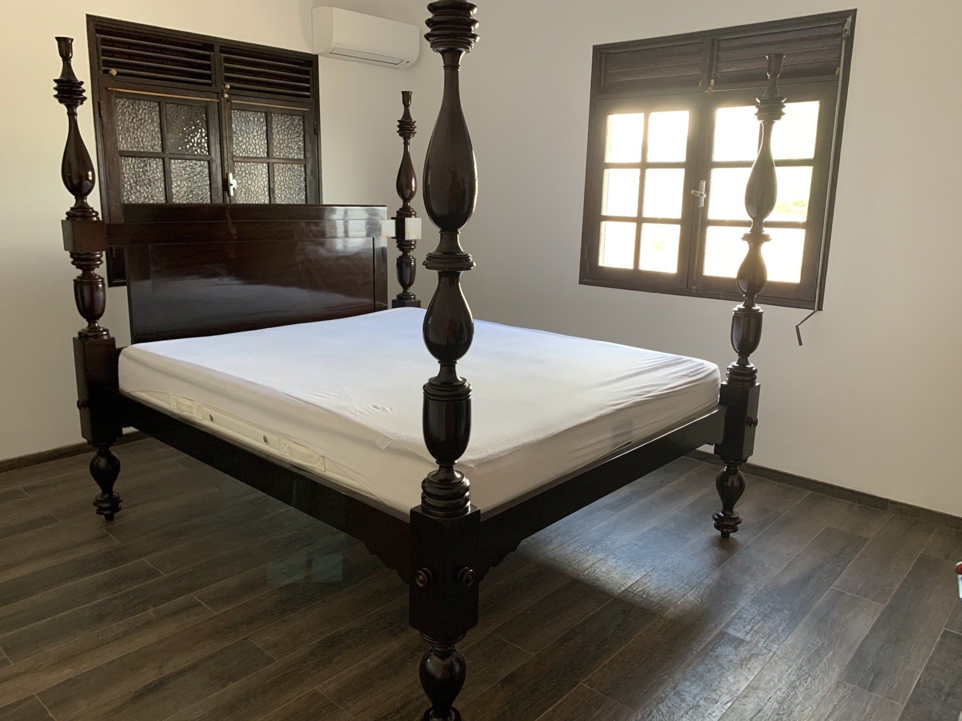 Lit à colonnes devant une fenêtre par un temps ensoleillé