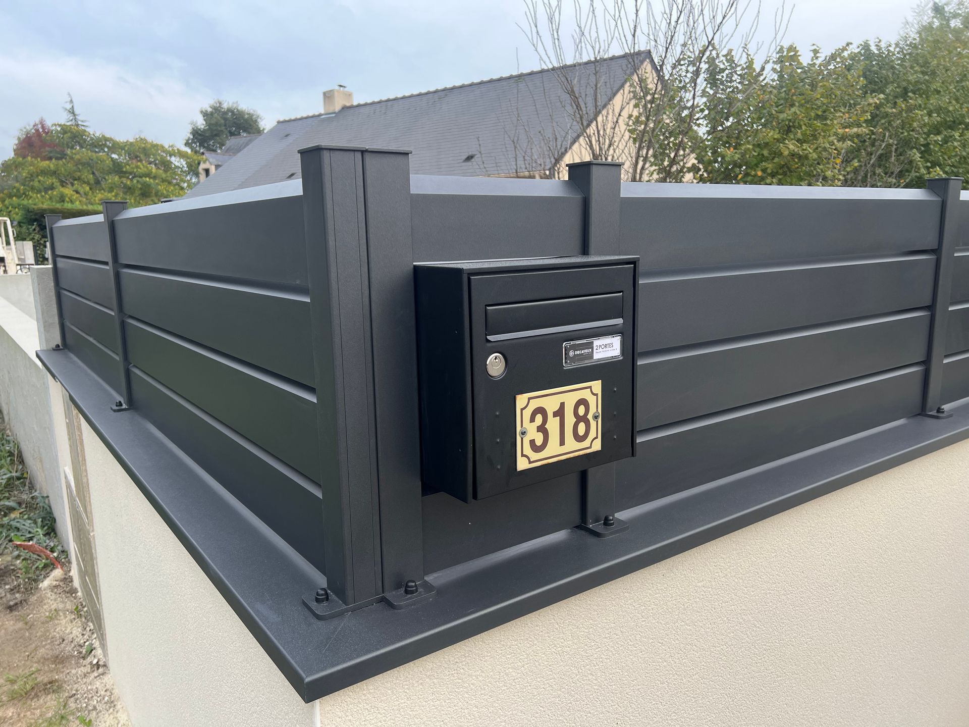 clôture aluminium modèle lame oblique avec boîte aux lettres intégrée, posée sur couvertine aluminium