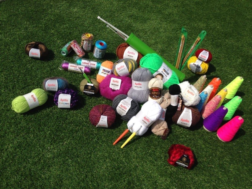 Un montón de hilo y agujas de crochet están tirados en el césped.