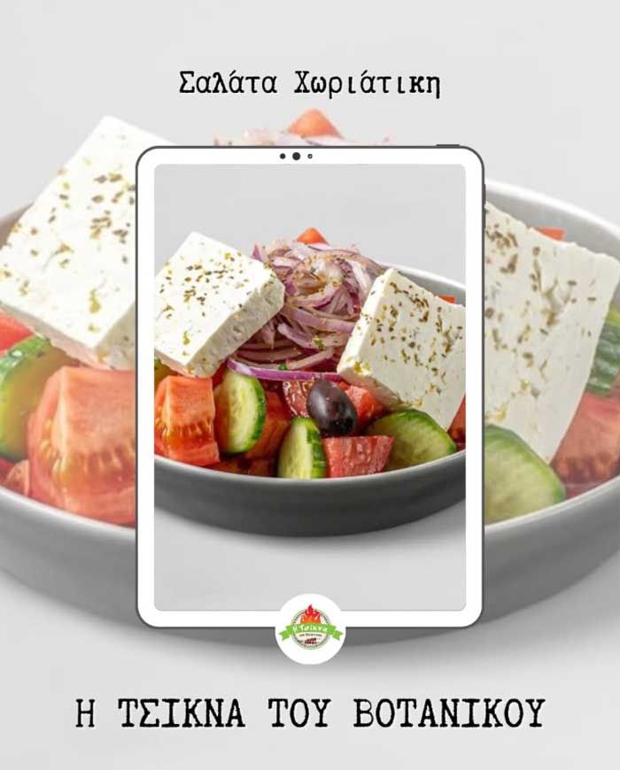 Ελληνική σαλάτα με φέτα, ντομάτες, αγγούρια, κρεμμύδια και ελιές σε μαύρο πιάτο, που φαίνεται σε πλαίσιο τηλεφώνου.