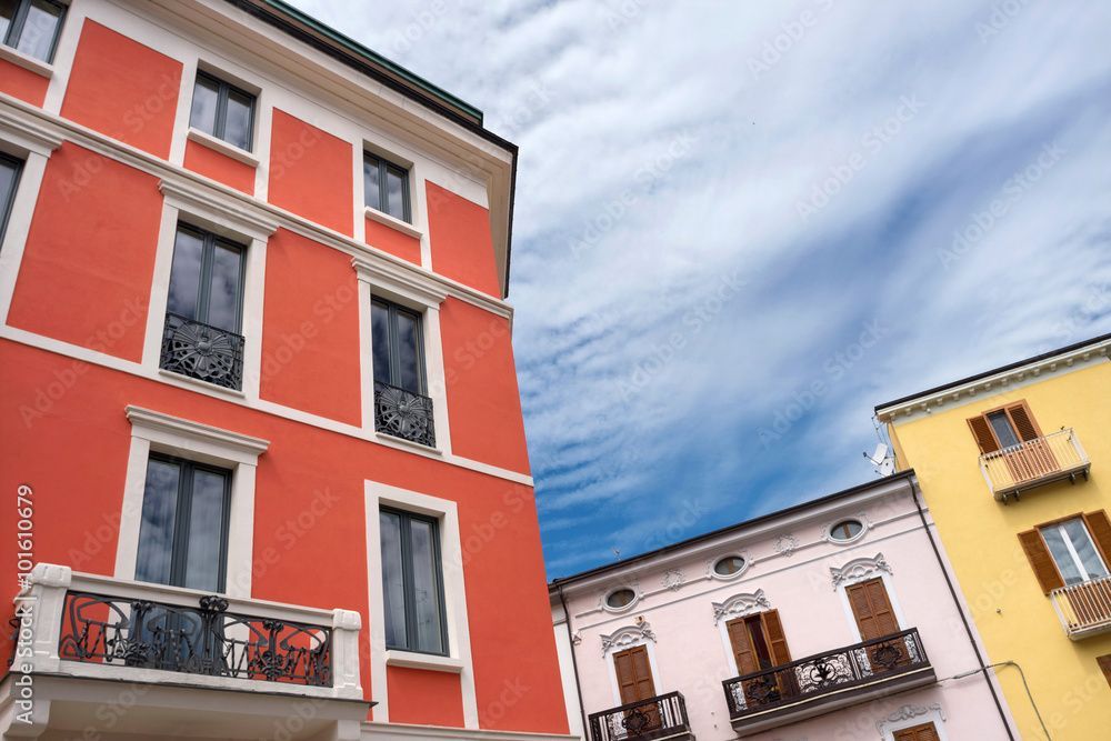 Ein rotes Gebäude mit Balkonen steht neben einem gelben Gebäude.