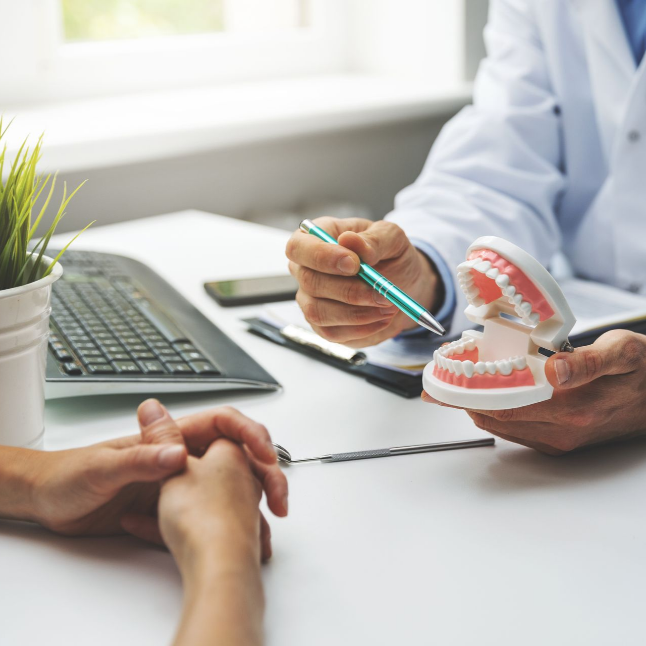 Le dentiste montre un modèle de dents au patient et explique le traitement.