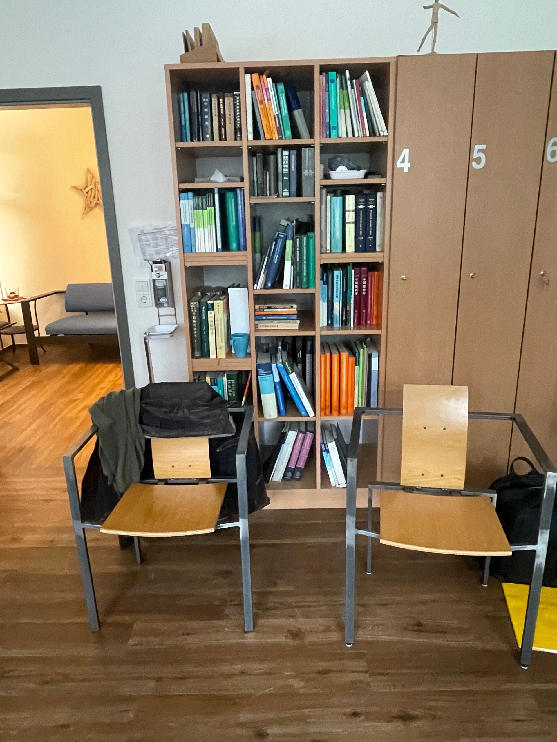 Zwei braune Stühle mit Kisten vor einem Bücherregal in einem Zimmer mit Holzboden.
