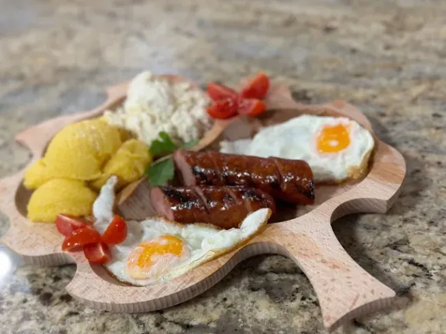 Una tabla de cortar de madera llena de comida sobre una mesa.