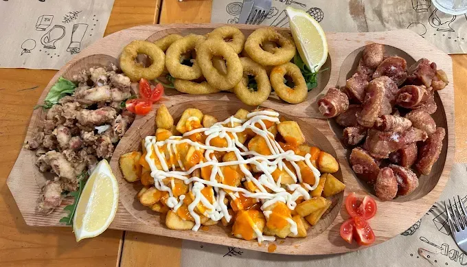 Una bandeja de madera llena de diferentes tipos de comida sobre una mesa.