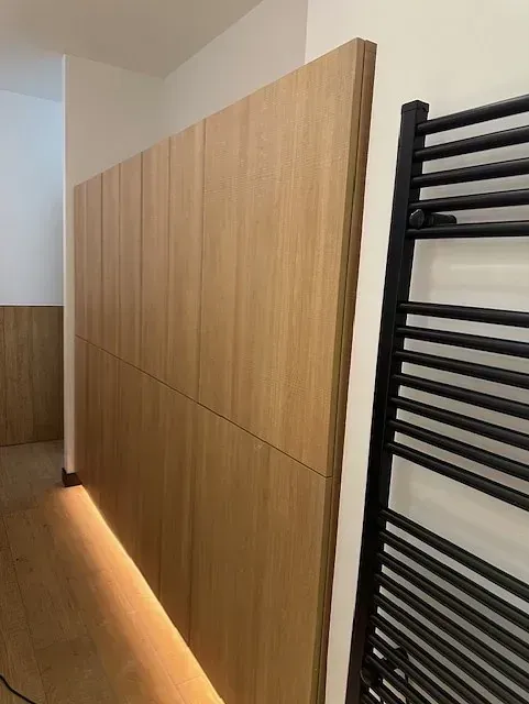 Un baño con una pared de madera y un toallero negro.