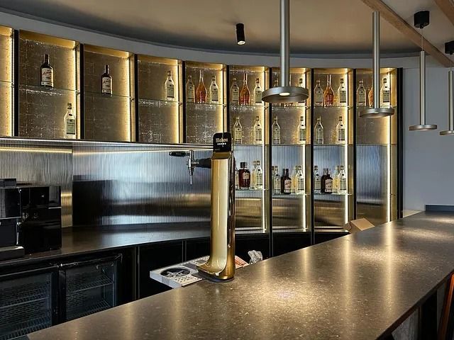 Un bar con muchas botellas en los estantes y una botella de cerveza en el mostrador.