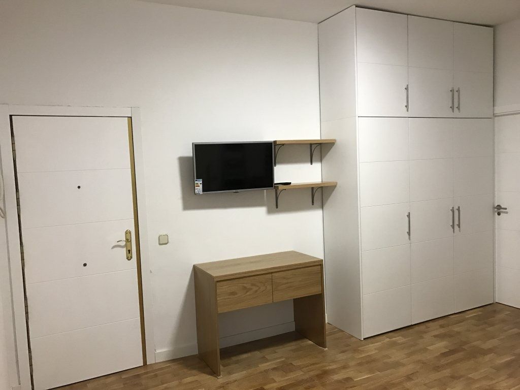 Una habitación con un escritorio y un televisor en la pared.
