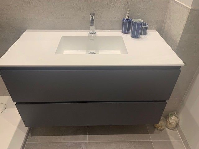 Un lavabo de baño con encimera blanca y grifo.