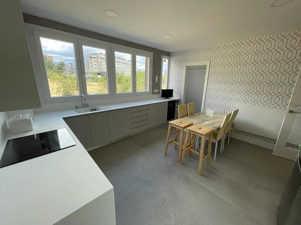 Una cocina con mesa y sillas y muchas ventanas.