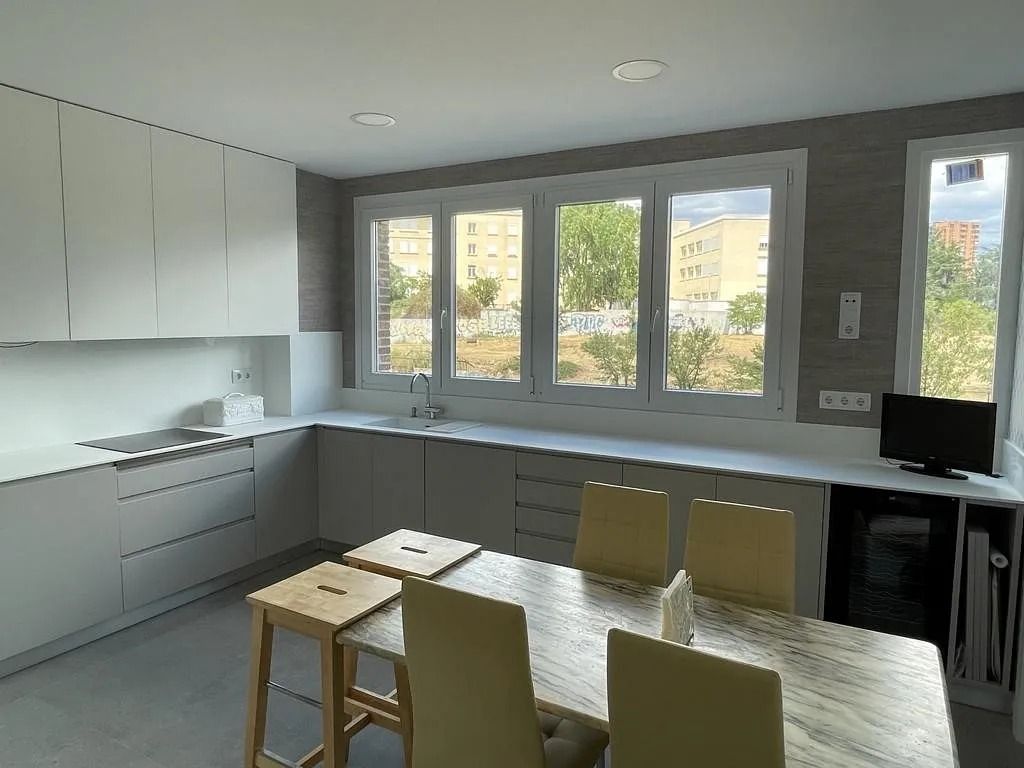 Una cocina con mesa y sillas y muchas ventanas.