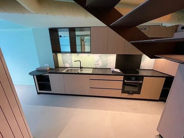 Una cocina con fregadero y escaleras que conducen a ella.