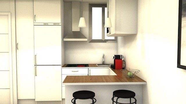 Una cocina con gabinetes blancos y taburetes negros.