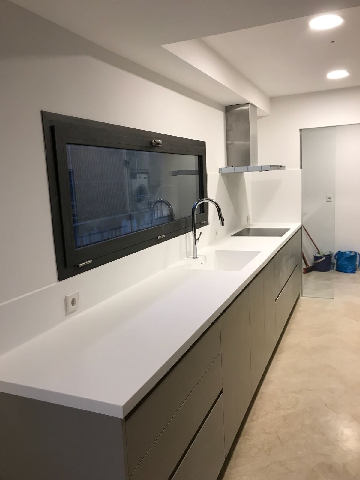Una cocina con fregadero, estufa y ventana.