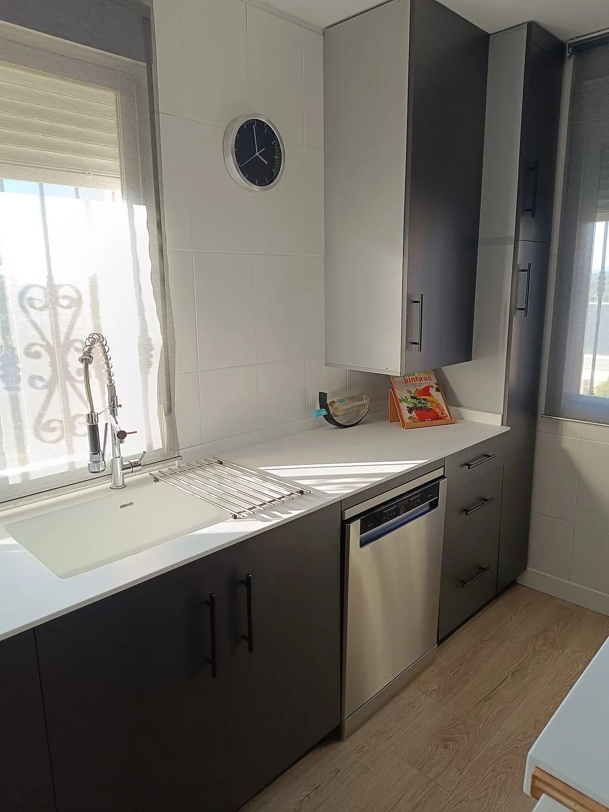 Una cocina con fregadero, lavavajillas y ventana.