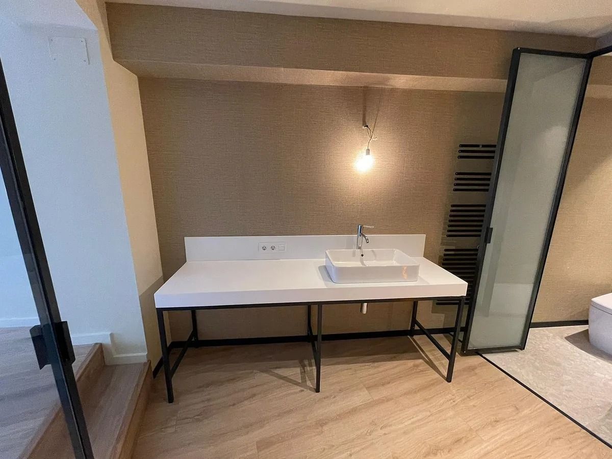 Un baño con lavabo y puerta de cristal.