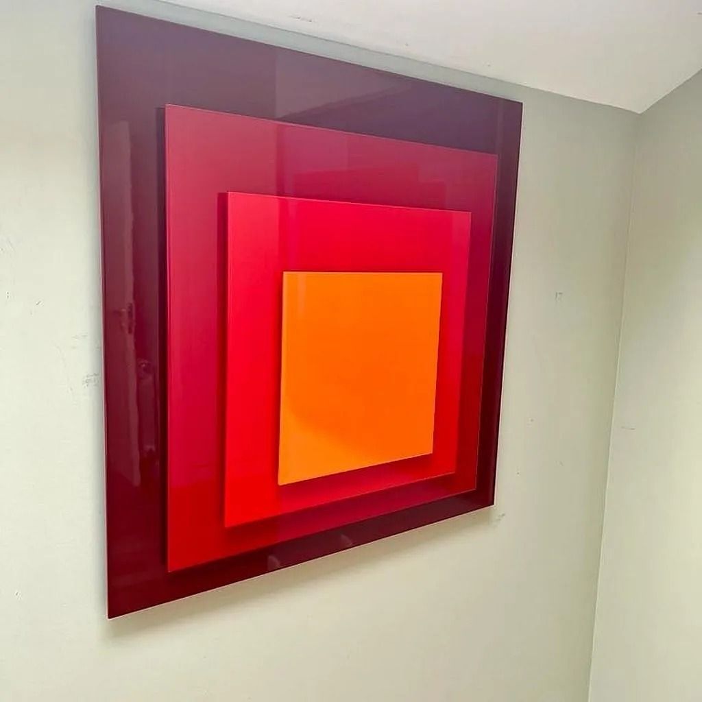 Un cuadrado rojo y naranja en una pared blanca.