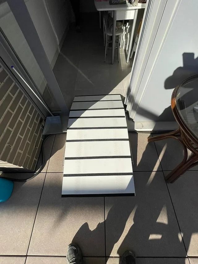 Una persona está de pie junto a un banco blanco sobre un piso de baldosas.