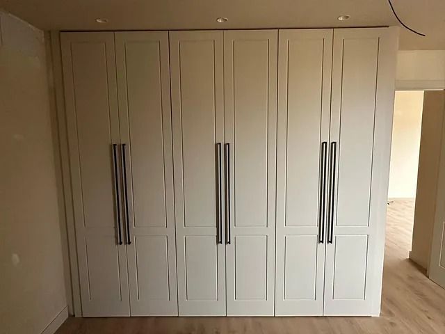 Un gran armario blanco con tiradores de acero inoxidable en una habitación.