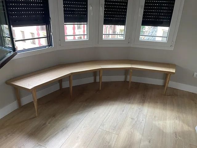 Un banco de madera está sentado en una habitación al lado de una ventana.