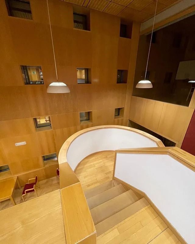 Una escalera en un edificio con paredes de madera y barandilla blanca.