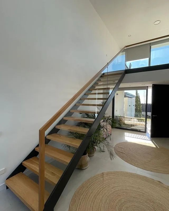 Una escalera con escalones de madera y barandilla negra.