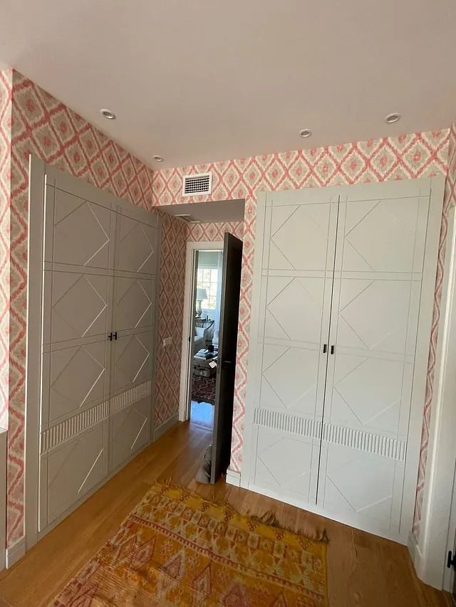 Una habitación con alfombra, armarios y una puerta que conduce a una sala de estar.