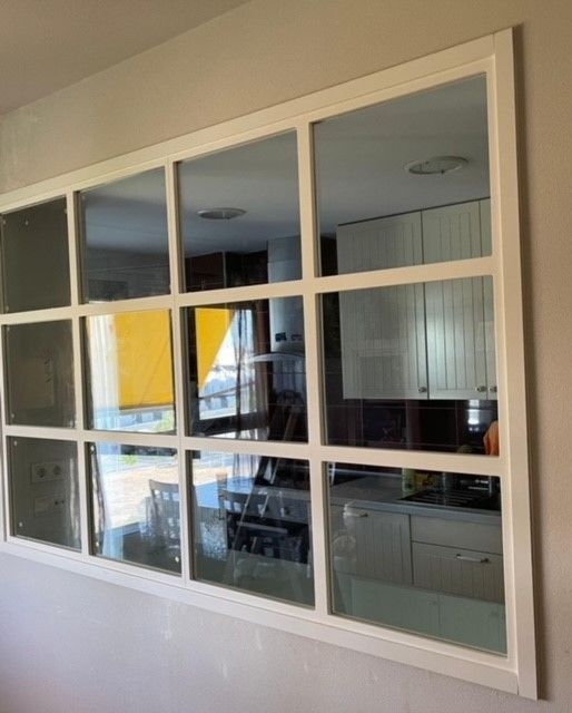 Una gran ventana con marco blanco da a una cocina.