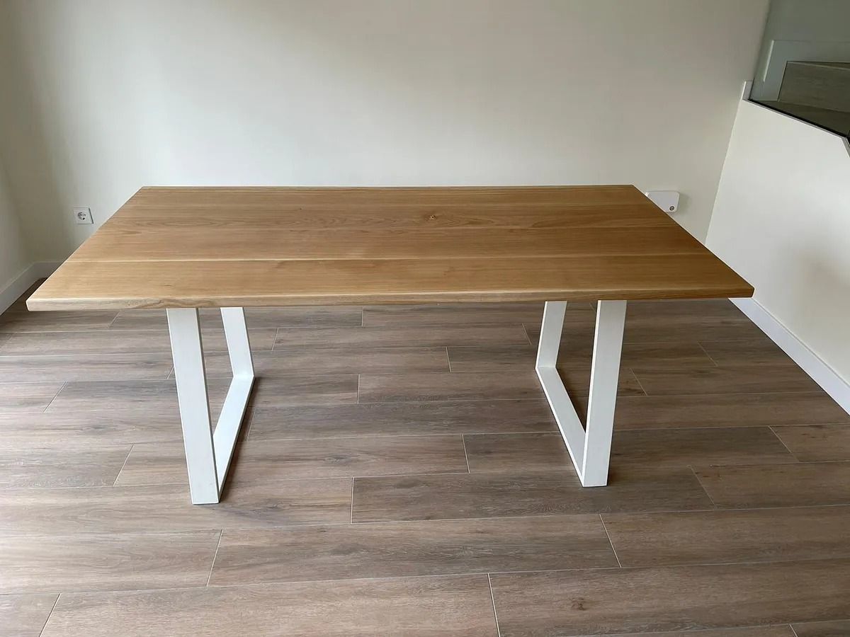Una mesa de madera con patas blancas está colocada sobre un piso de madera en una habitación.