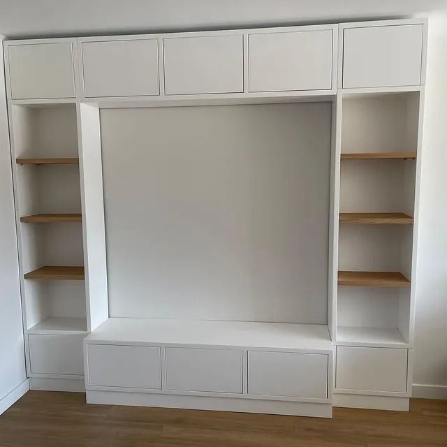 Un centro de entretenimiento blanco con estantes y gabinetes de madera en una sala de estar.