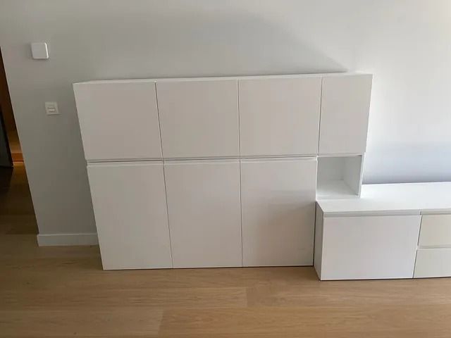 Un armario blanco está colocado sobre un piso de madera en una sala de estar.