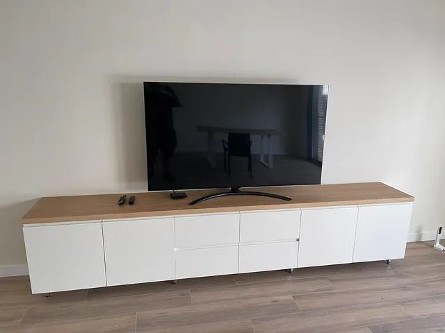 Un televisor de pantalla plana está colocado encima de un centro de entretenimiento blanco.