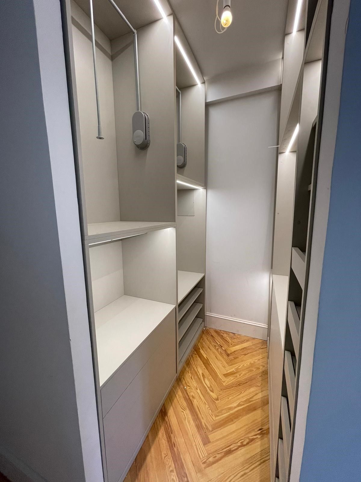 Un vestidor con pisos de madera y una luz en el techo.