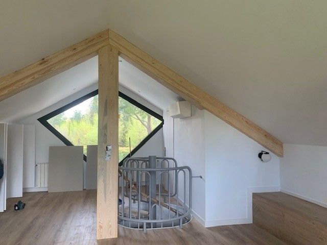Un ático con una escalera de caracol y una gran ventana.