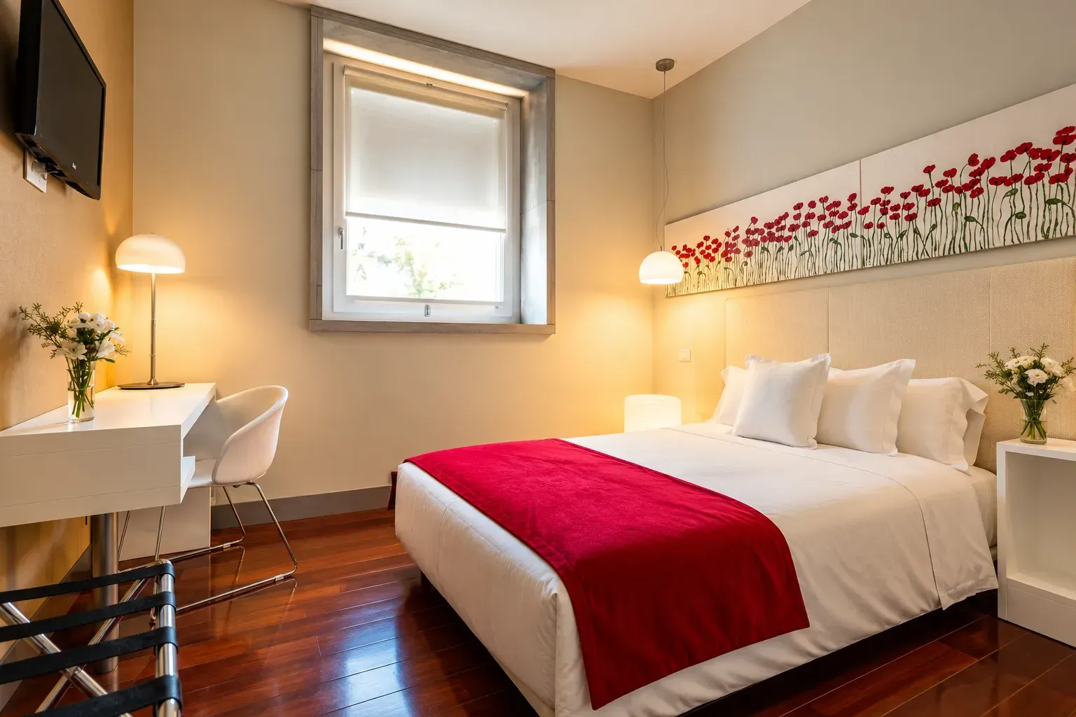 Dormitorio moderno con colcha roja, ropa de cama blanca, escritorio y ventana con cortinas grises