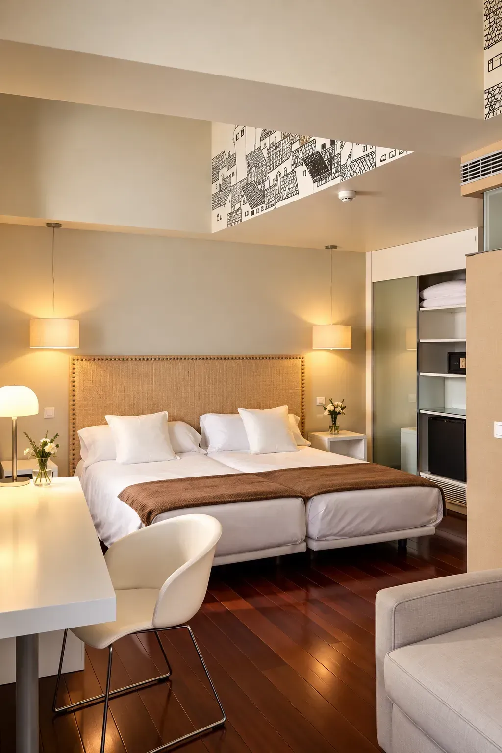 Dormitorio moderno con una cama grande, lámparas cálidas, suelo de madera y una pequeña zona de escritorio