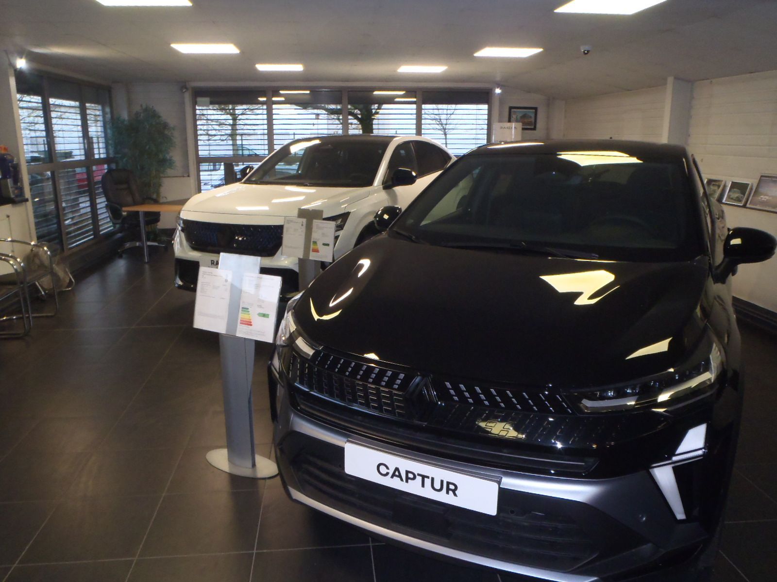 SUV Captur noir dans une salle d'exposition, SUV blanc en arrière-plan.