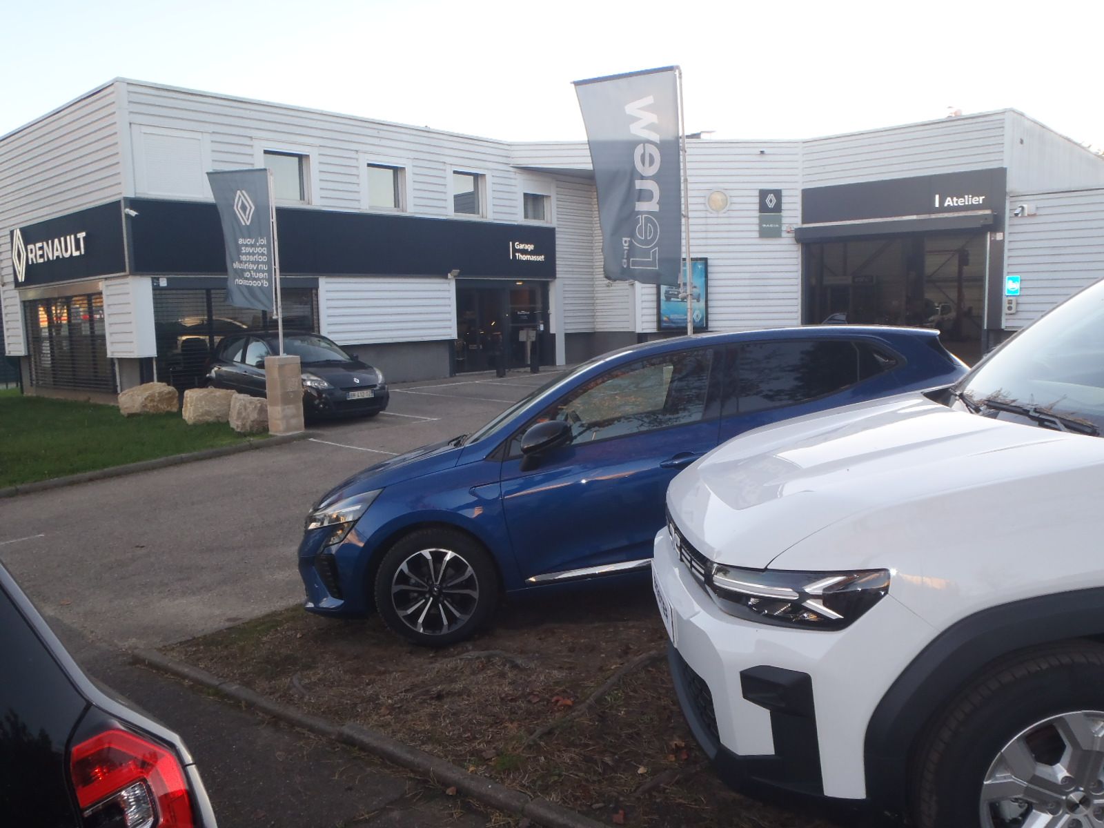 Une concession Renault avec des voitures exposées, des véhicules bleus et blancs à l'avant.
