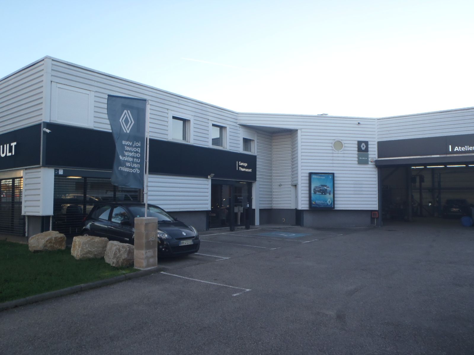 Extérieur d'une concession Renault avec une voiture noire garée devant.
