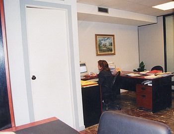 Una persona está sentada en un escritorio en una oficina profesional, trabajando en una computadora.