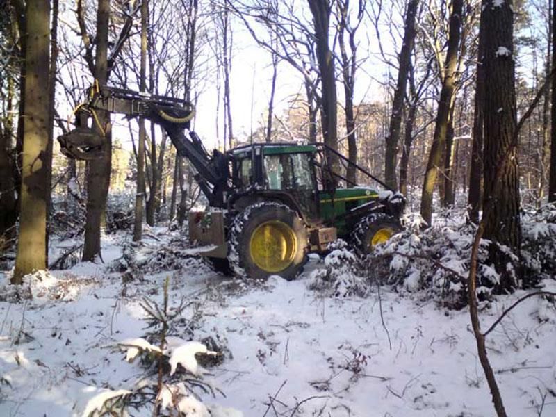 Ein John Deere Traktor fährt durch einen verschneiten Wald